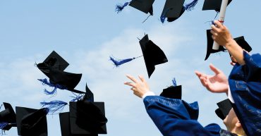 Estudiantes lanzando sus birretes al aire en una graduación