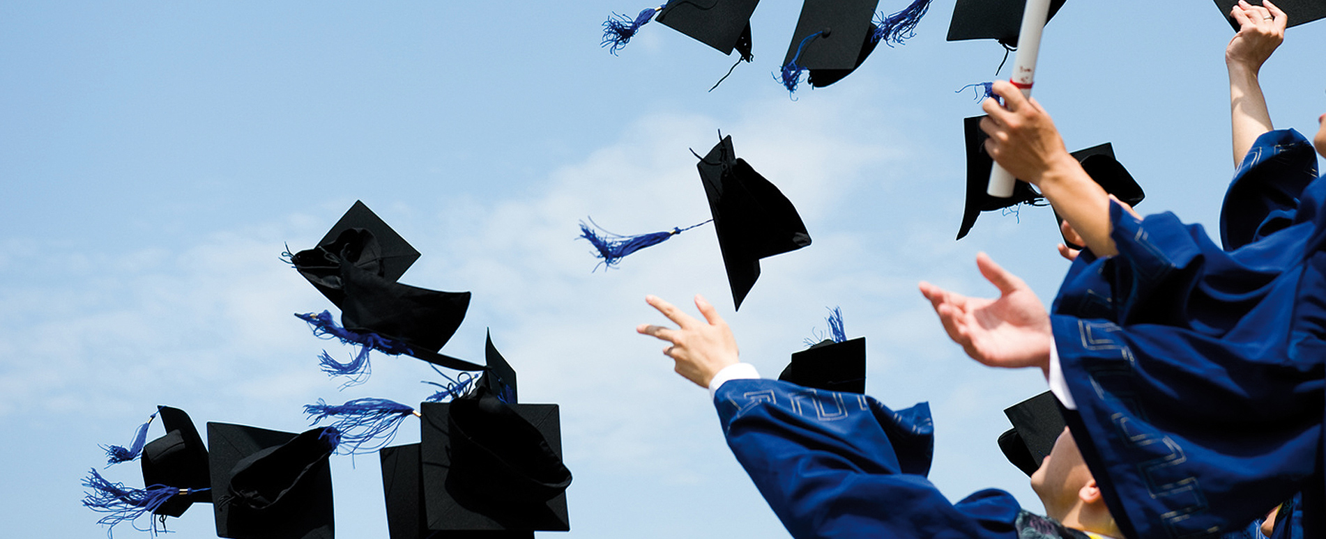 Estudiantes lanzando sus birretes al aire en una graduación